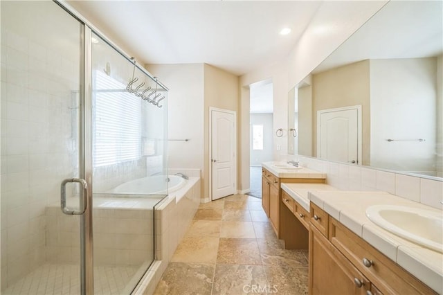 bathroom with a bath, a stall shower, two vanities, and a sink