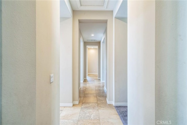 hallway with stone tile flooring and baseboards
