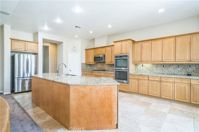 kitchen with light stone countertops, tasteful backsplash, visible vents, a sink, and stainless steel appliances