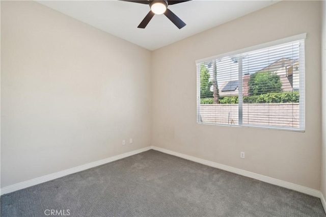 empty room featuring baseboards, dark carpet, and ceiling fan