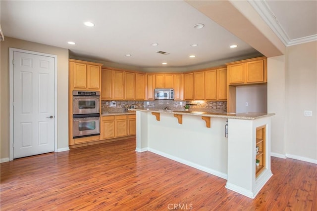 kitchen with decorative backsplash, appliances with stainless steel finishes, light wood finished floors, and visible vents