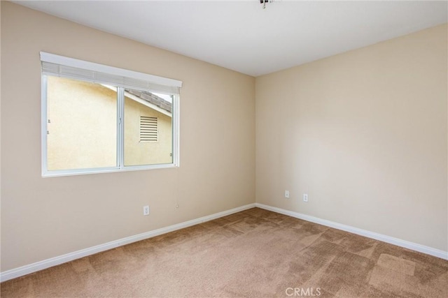 spare room featuring carpet flooring and baseboards