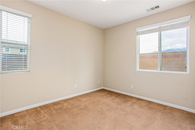 empty room with light carpet, visible vents, and baseboards