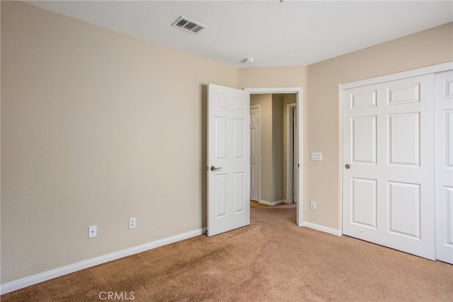 unfurnished bedroom featuring light carpet, a closet, baseboards, and visible vents