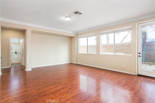 spare room with wood finished floors, ornamental molding, and a wealth of natural light