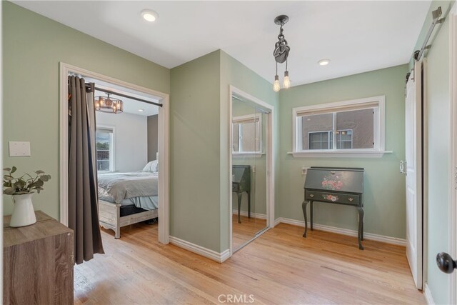 14844 Lull St, Van Nuys, CA 91405 - hallway featuring an inviting chandelier, light wood-style flooring, a barn door, recessed lighting, and baseboards