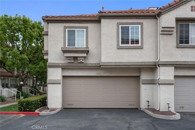9876 Arrow Unit 1, Rancho Cucamonga, CA 91730 - view of property featuring stucco siding, an attached garage, a tiled roof, and driveway