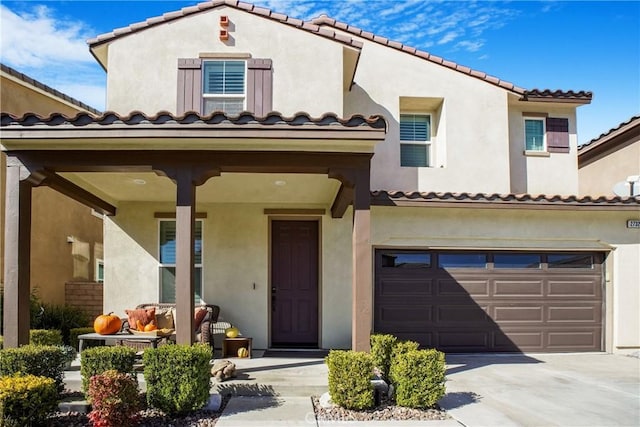 mediterranean / spanish house with concrete driveway, a tiled roof, stucco siding, and a garage