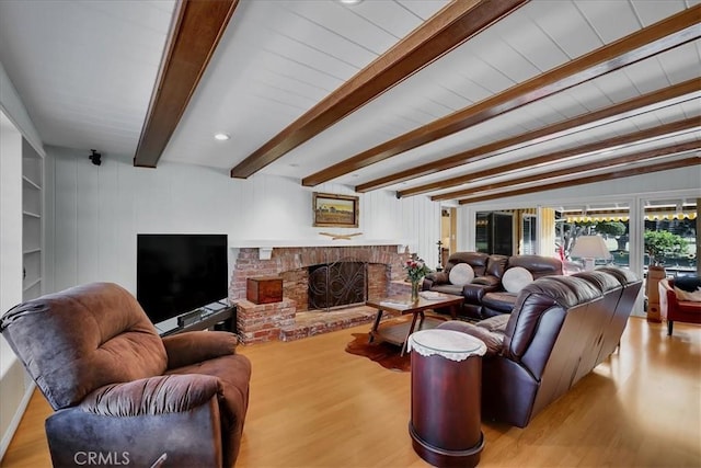 living area with wood finished floors, beamed ceiling, and a fireplace