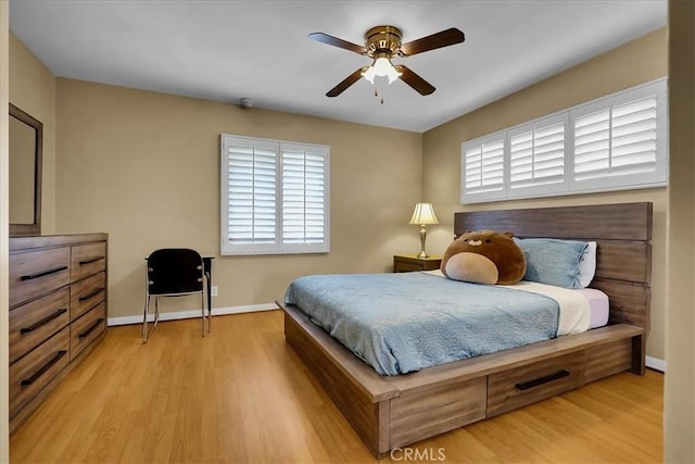 bedroom with light wood-style flooring, baseboards, and a ceiling fan