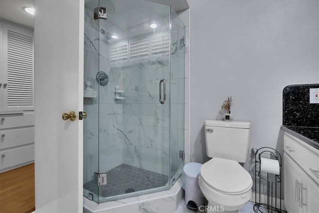 bathroom featuring toilet, a stall shower, and vanity