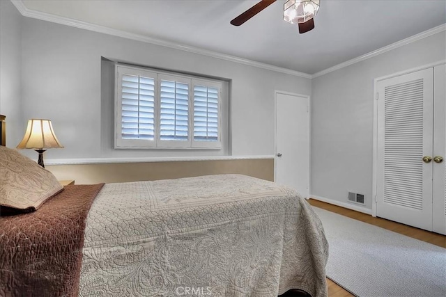 bedroom featuring crown molding, a ceiling fan, visible vents, wood finished floors, and baseboards