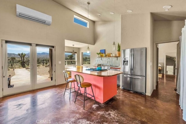53105 Chia Trl, Pioneertown, CA 92268 - kitchen featuring concrete floors, a center island, stainless steel fridge, a wall mounted air conditioner, and a kitchen bar