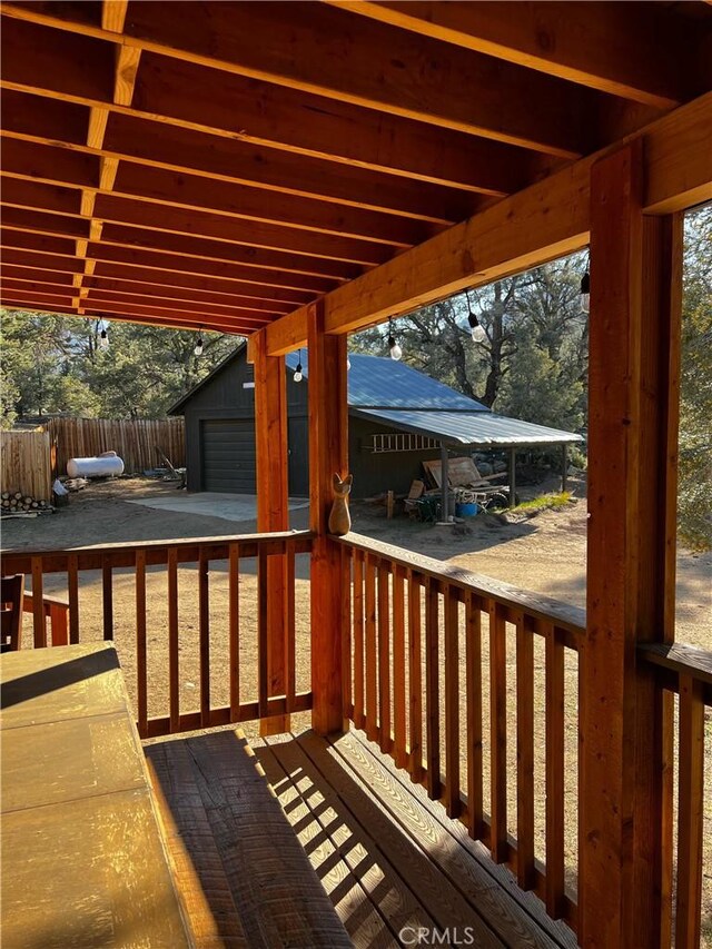 wooden terrace with a garage, fence, and an outbuilding