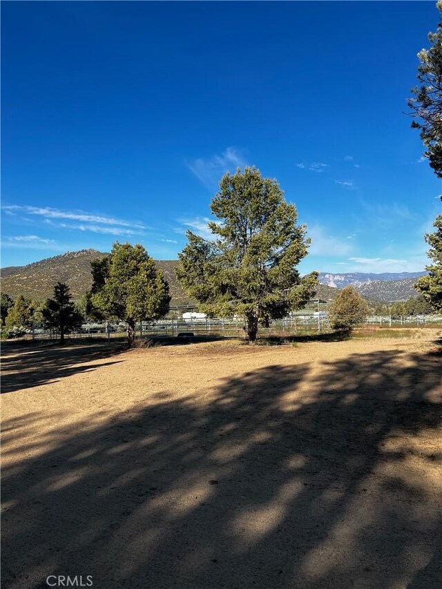 view of yard with a rural view, a mountain view, and fence