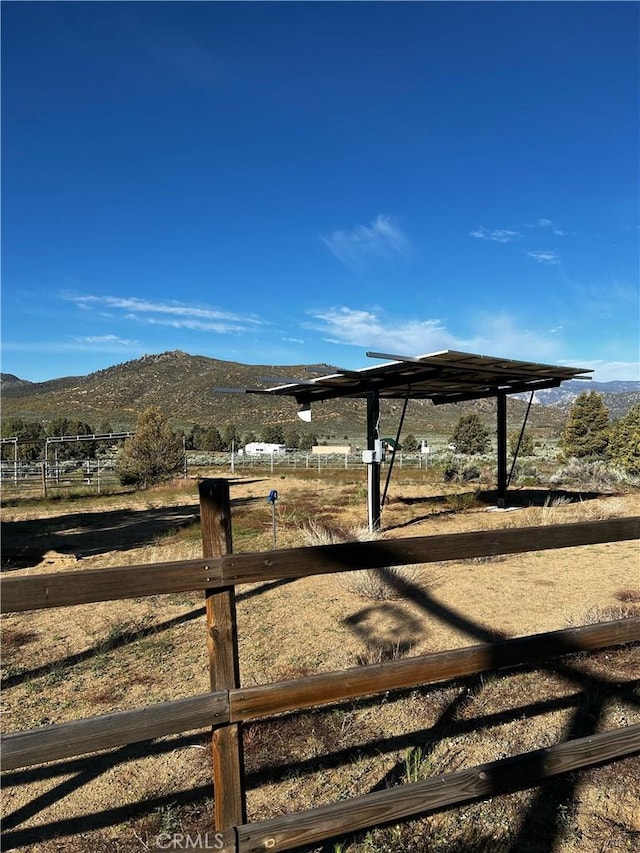 view of yard with a rural view, fence, and a mountain view
