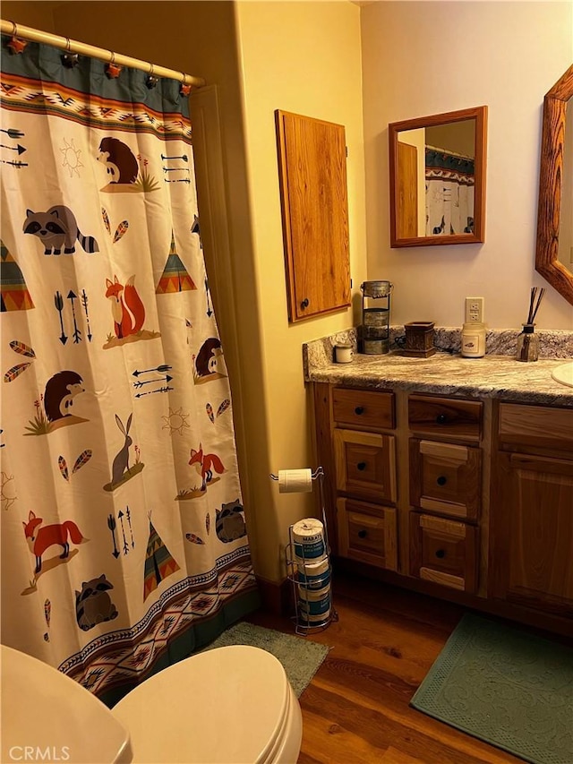 full bath featuring toilet, curtained shower, wood finished floors, and vanity