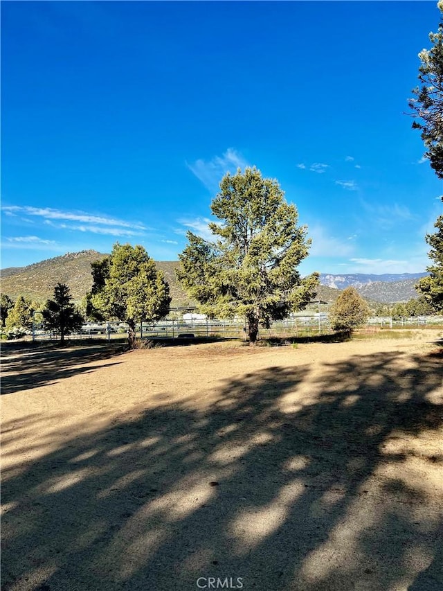 view of yard with fence, a rural view, and a mountain view