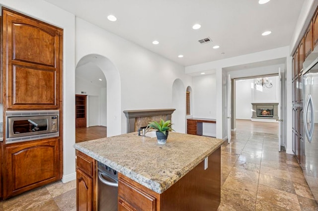 4033 Keri Way, Fallbrook, CA 92028 - kitchen featuring stainless steel appliances, a kitchen island, a glass covered fireplace, arched walkways, and stone tile flooring