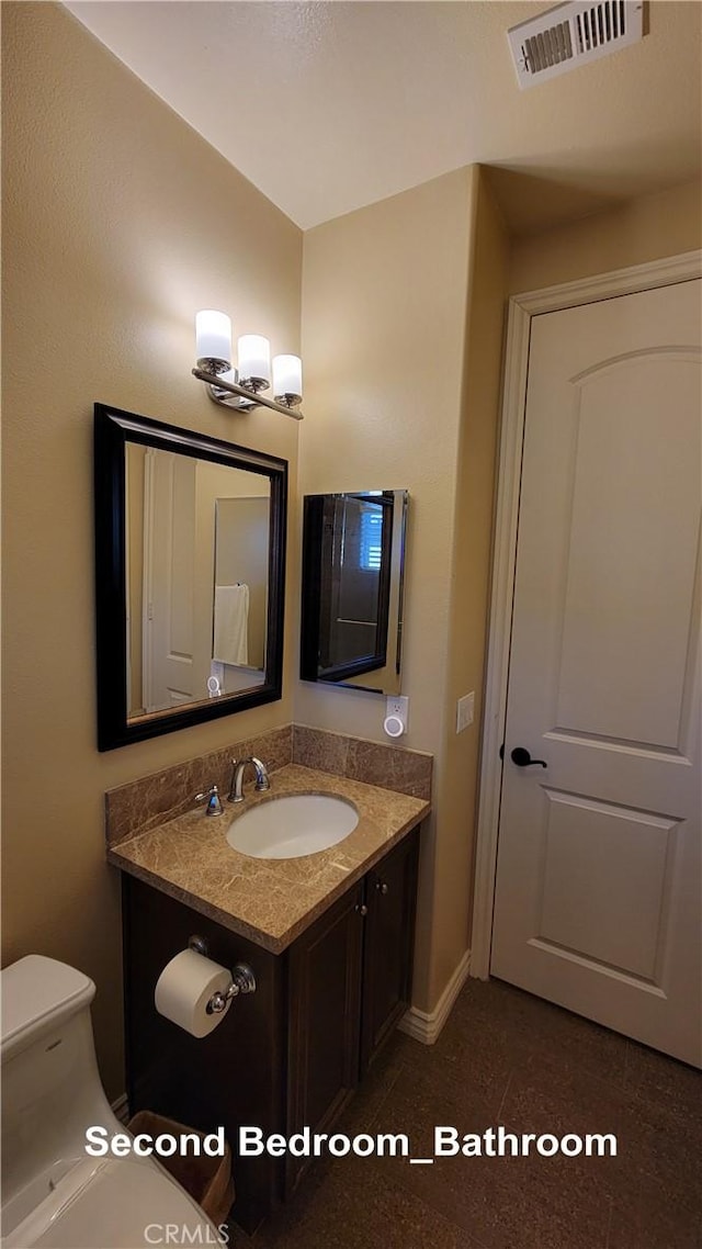 half bath featuring toilet, visible vents, and vanity
