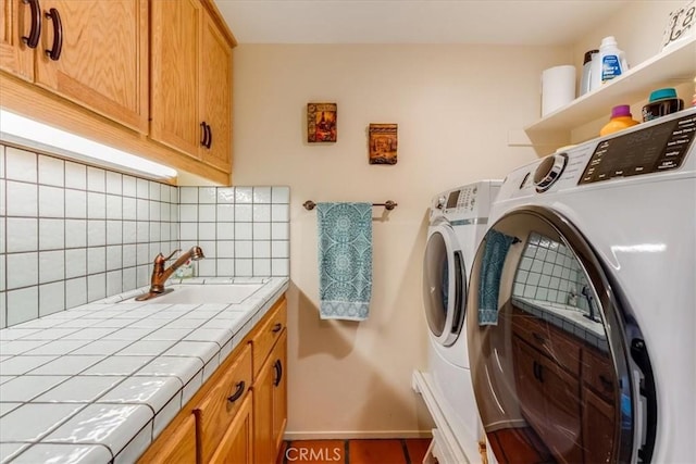 laundry room with baseboards, washing machine and clothes dryer, a sink, and cabinet space