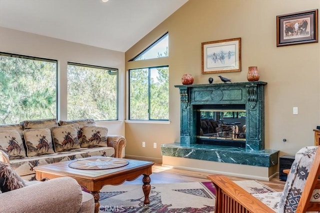 living area featuring wood finished floors, high vaulted ceiling, a high end fireplace, and baseboards