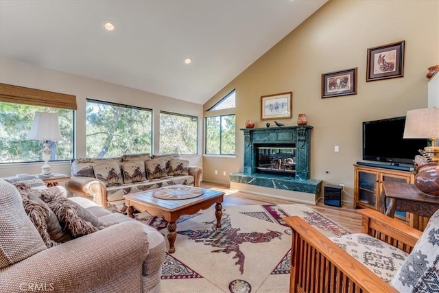 living room featuring baseboards, recessed lighting, wood finished floors, high vaulted ceiling, and a premium fireplace