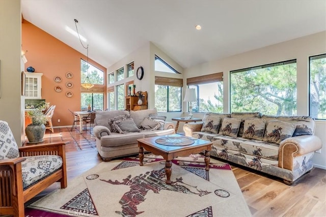 living area with a healthy amount of sunlight, high vaulted ceiling, and wood finished floors