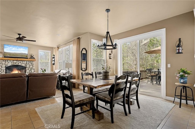 dining area featuring light tile patterned floors, a wealth of natural light, ceiling fan, and a fireplace