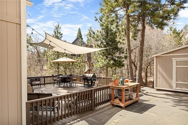 deck featuring area for grilling, outdoor dining space, a storage unit, and an outbuilding