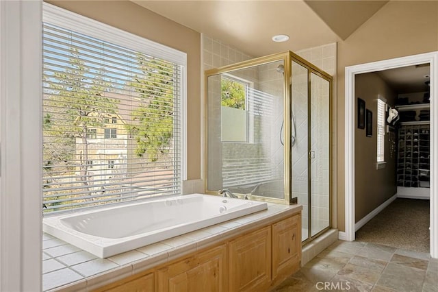 full bathroom with a walk in closet, baseboards, a shower stall, and a garden tub