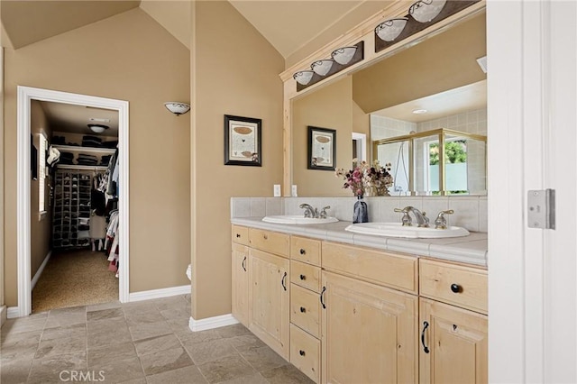 full bathroom featuring a shower stall, a walk in closet, vaulted ceiling, and a sink