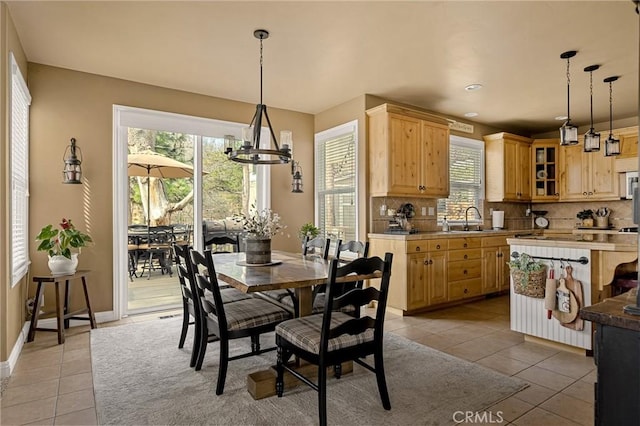 dining space featuring a wealth of natural light, baseboards, a chandelier, and light tile patterned flooring