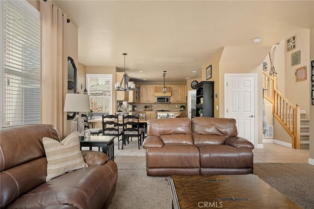 living room featuring light tile patterned flooring, baseboards, and stairway
