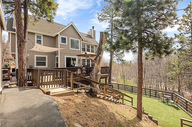 rear view of house with a yard, fence, a chimney, a shingled roof, and a deck