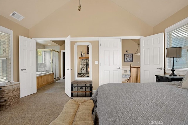 carpeted bedroom with high vaulted ceiling, ensuite bath, visible vents, and multiple windows