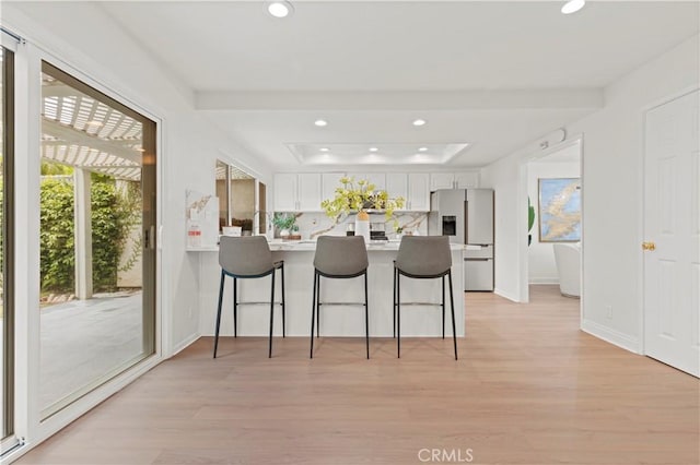 49 W Yale Loop Unit 26, Irvine, CA 92604 - kitchen featuring stainless steel fridge, a breakfast bar, light wood finished floors, white cabinetry, and recessed lighting