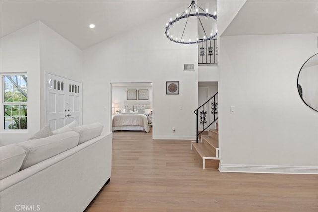 49 W Yale Loop Unit 26, Irvine, CA 92604 - living room with high vaulted ceiling, a chandelier, light wood-type flooring, stairs, and baseboards