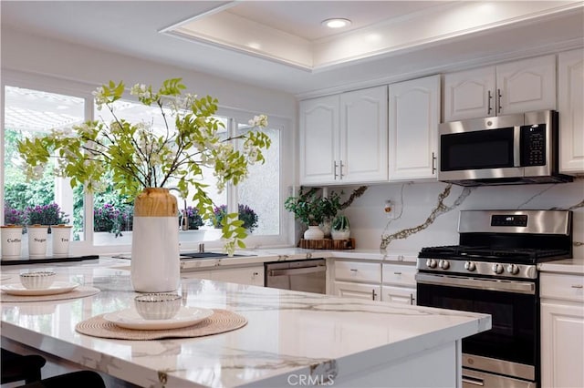 49 W Yale Loop Unit 26, Irvine, CA 92604 - kitchen featuring stainless steel appliances, white cabinets, light stone counters, a raised ceiling, and recessed lighting