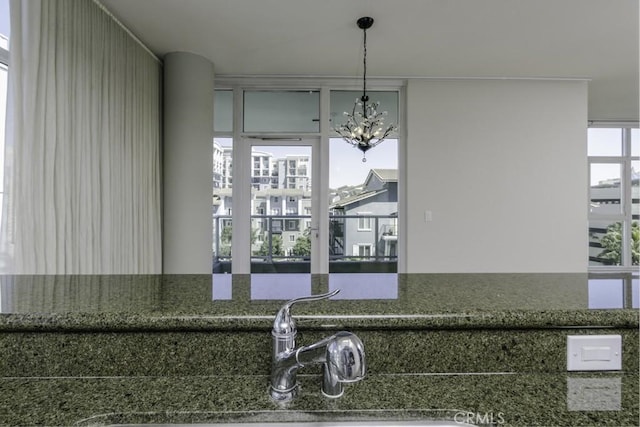 room details featuring decorative light fixtures, dark stone countertops, an inviting chandelier, and a sink