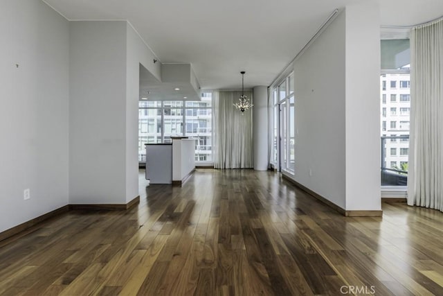 unfurnished dining area with a notable chandelier, baseboards, and dark wood-style floors