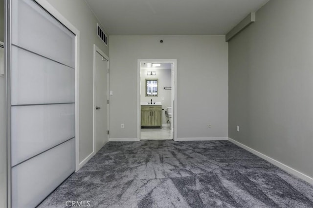 unfurnished bedroom with visible vents, baseboards, ensuite bathroom, a sink, and carpet flooring