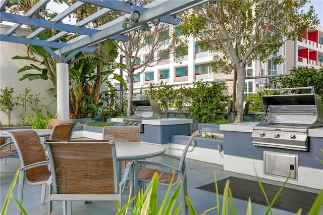 view of patio featuring exterior kitchen, outdoor dining area, area for grilling, and a pergola
