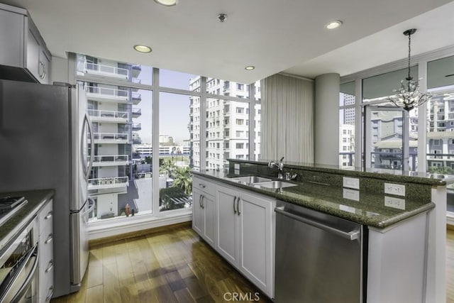 kitchen featuring dark stone countertops, wood finished floors, a view of city, a sink, and stainless steel appliances