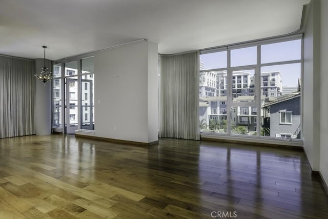 empty room featuring a chandelier, a wealth of natural light, and a wall of windows