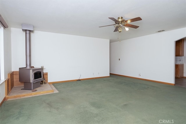 50566 Critter Creek Ln, Oakhurst, CA 93644 - unfurnished living room with a wood stove, ceiling fan, carpet floors, baseboards, and arched walkways