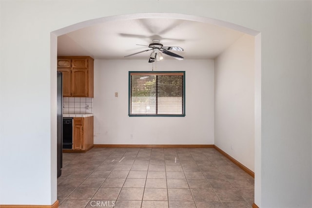 50566 Critter Creek Ln, Oakhurst, CA 93644 - unfurnished dining area with arched walkways, ceiling fan, light tile patterned flooring, and baseboards