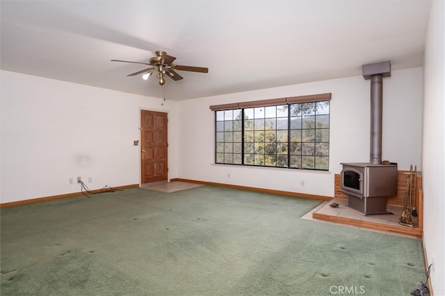 50566 Critter Creek Ln, Oakhurst, CA 93644 - unfurnished living room featuring carpet floors, a wood stove, ceiling fan, and baseboards