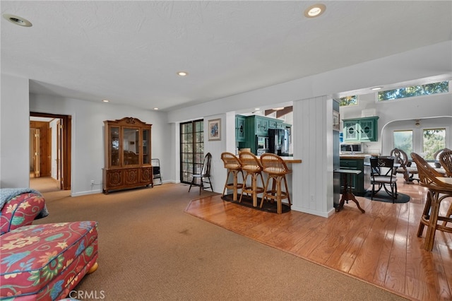 living area featuring carpet floors, baseboards, recessed lighting, and wood finished floors