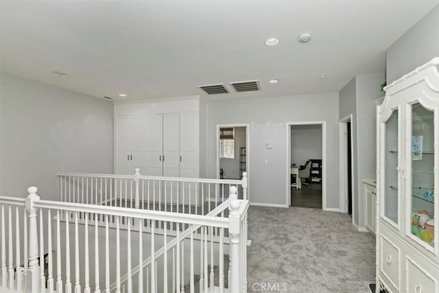 hallway with recessed lighting, an upstairs landing, visible vents, and carpet floors